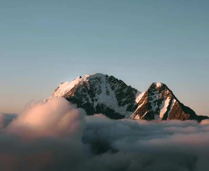 a mountain covered in clouds under a blue sky, an album cover, pexels contest winner, high elevation, early morning light, brown, 1 2 9 7