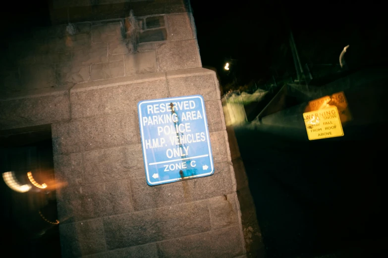 a blue sign sitting on the side of a building, a poster, inspired by Elsa Bleda, unsplash, moonlit parking lot, sitting in a cemetery at night, 2000s photo, secret service photos