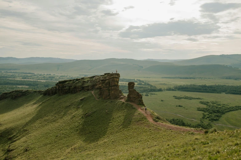 a man standing on top of a lush green hillside, by Muggur, unsplash contest winner, les nabis, sci - fi mongolian village, in the distance is a rocky hill, 000 — википедия, vostok-1