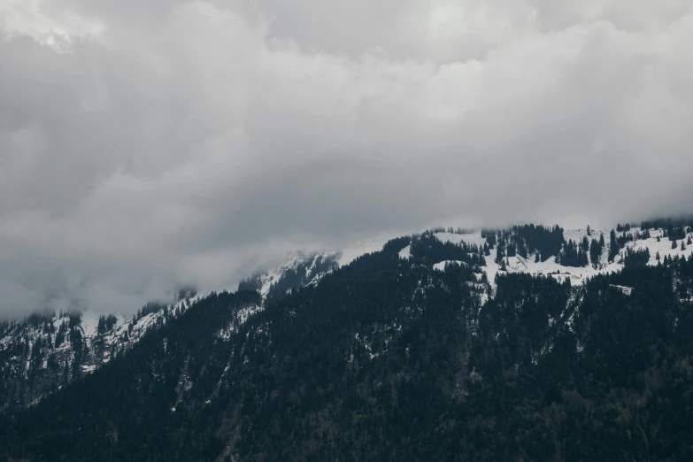 a plane flying over a mountain covered in snow, pexels contest winner, figuration libre, overcast gray skies, ominous! landscape of north bend, hill with trees, cinematic 4 k wallpaper