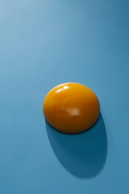 an egg sitting on top of a blue surface, by Doug Ohlson, amber, giant sun, complementary colour, resin