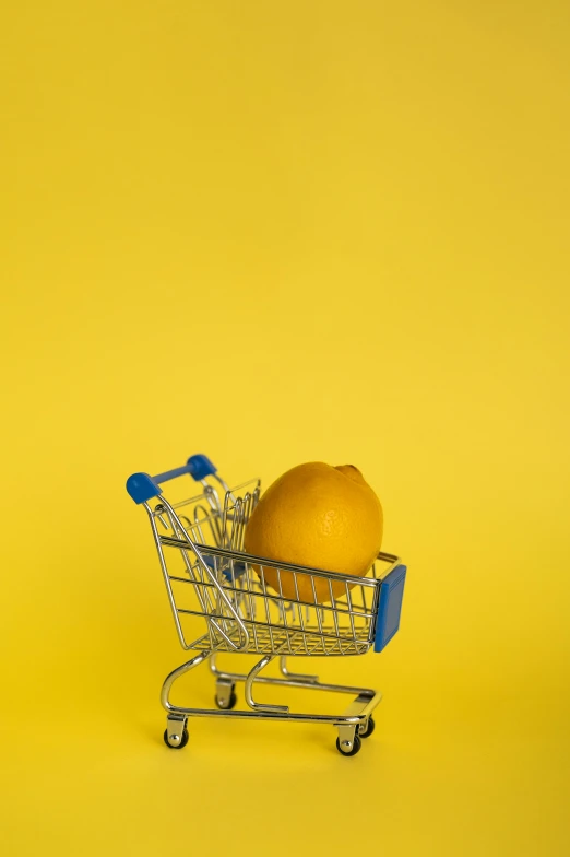 an orange in a shopping cart on a yellow background, pexels, blue orange, made of food, 1.2
