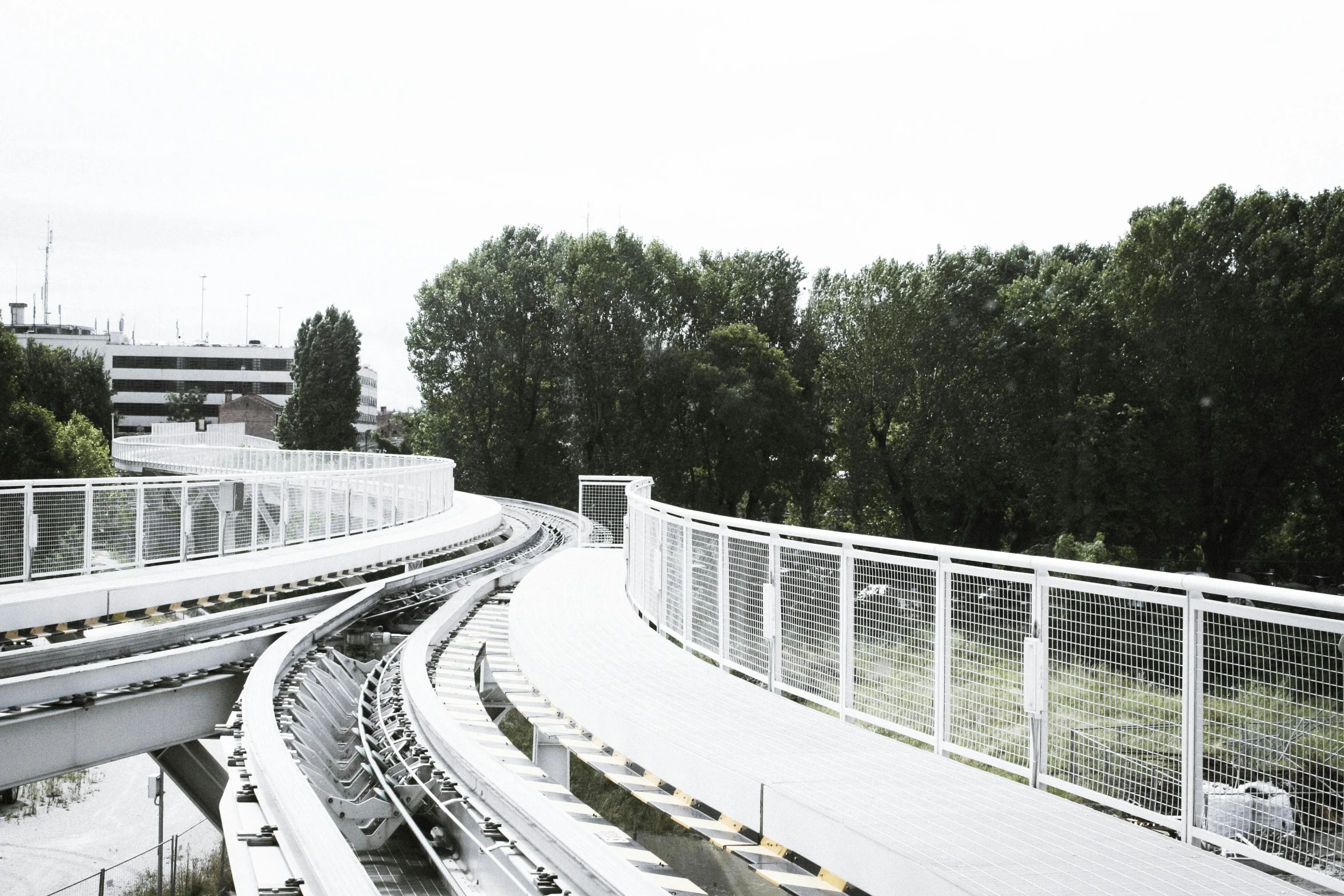 a train traveling down tracks next to a forest, inspired by Zaha Hadid, unsplash, happening, white pale concrete city, benches, monorail station, grey