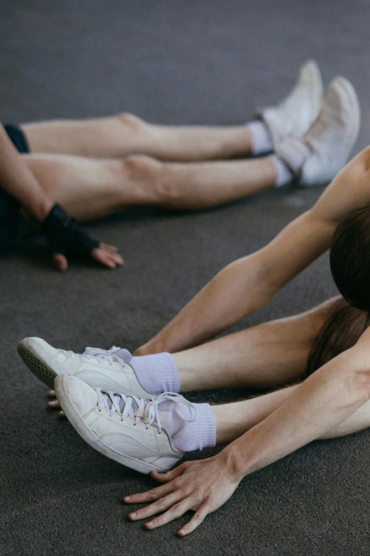 a couple of people that are laying on the ground, by Nina Hamnett, trending on unsplash, renaissance, in a gym, detailed legs, non-binary, low quality photo