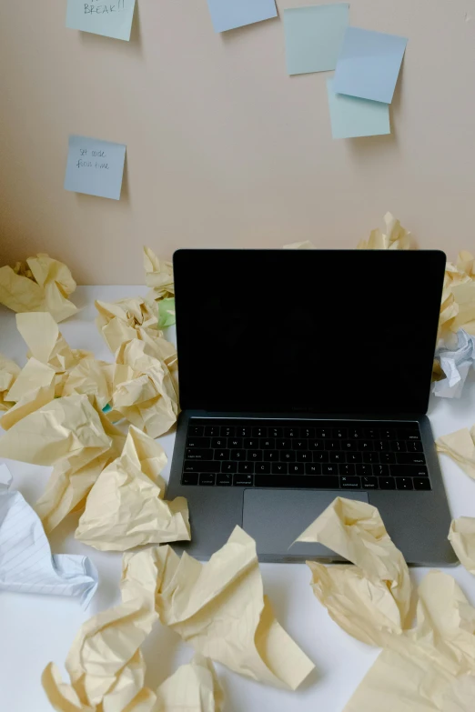 a laptop computer sitting on top of a table covered in sticky notes, some wrinkled, brown paper, turbulence, anna nikonova