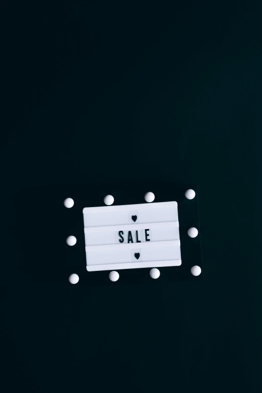 a white sale sign on a black background, a cartoon, trending on unsplash, tactile buttons and lights, vintage film, thumbnail, indigo