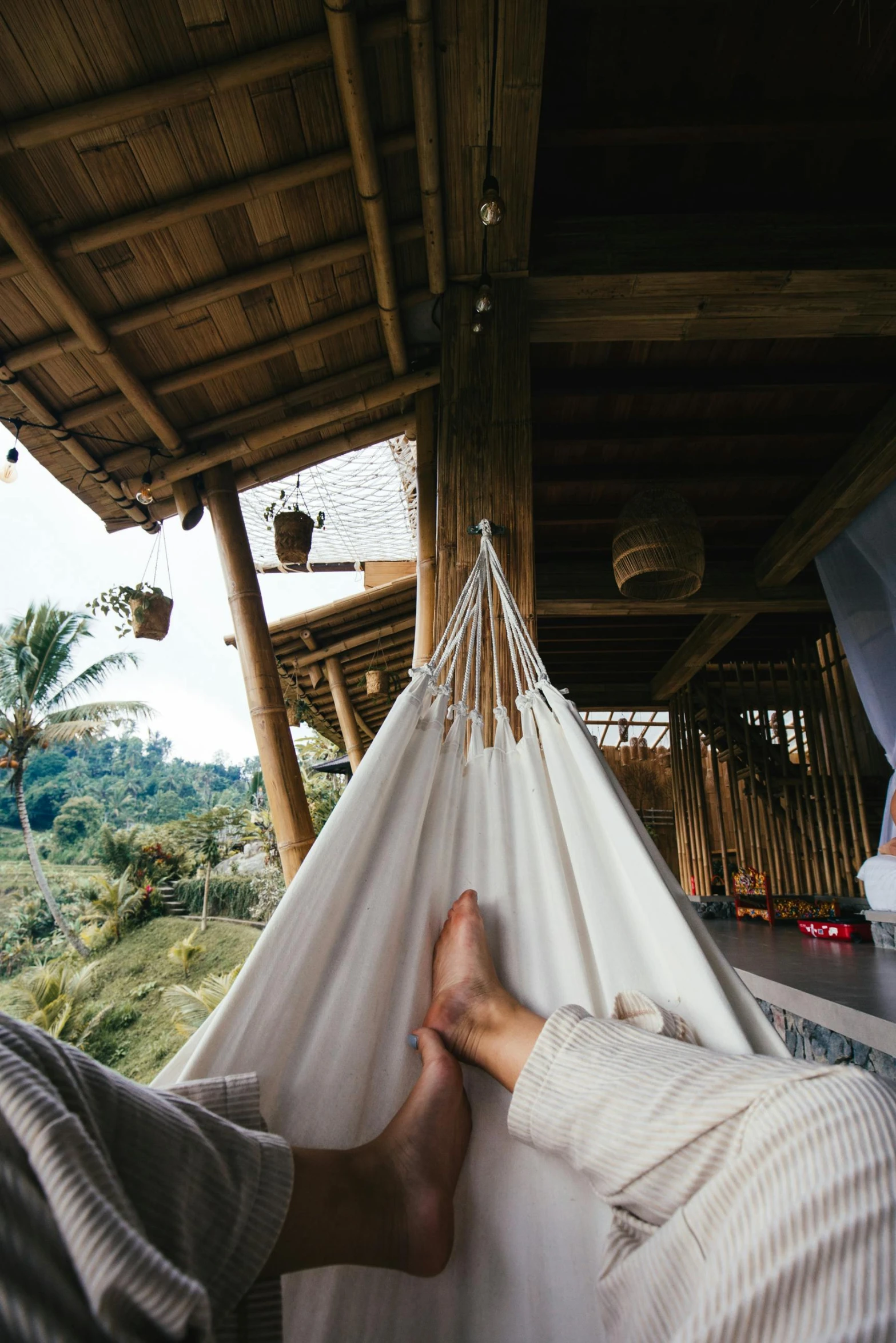 a person laying in a hammock on a porch, trending on unsplash, bamboo huts, lush vista, ecovillage, relaxing on a couch