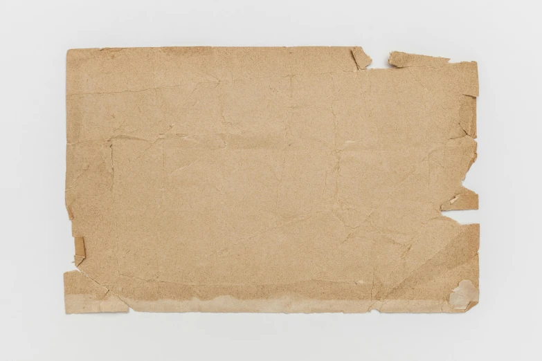 a piece of brown paper on a white surface, by Joseph Beuys, trending on pexels, fluxus, background image, cardboard cutout, realistic old photo