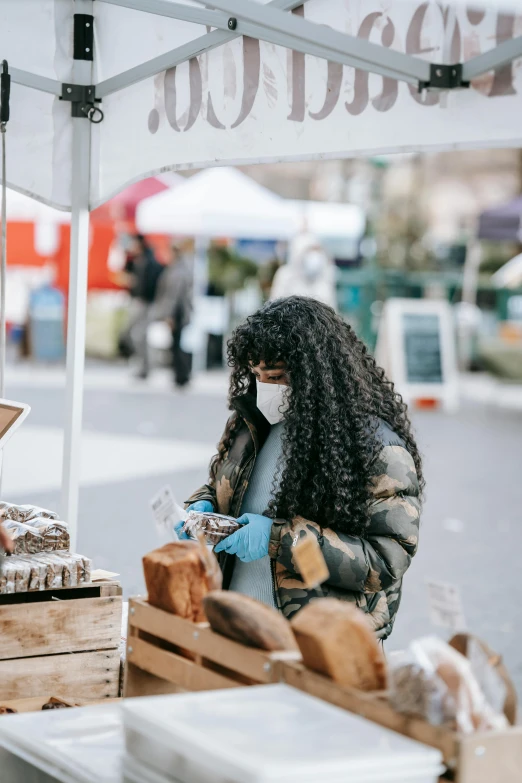 a woman wearing a face mask at a farmers market, trending on pexels, renaissance, bending down slightly, sza, wearing a turtleneck and jacket, trading illegal goods