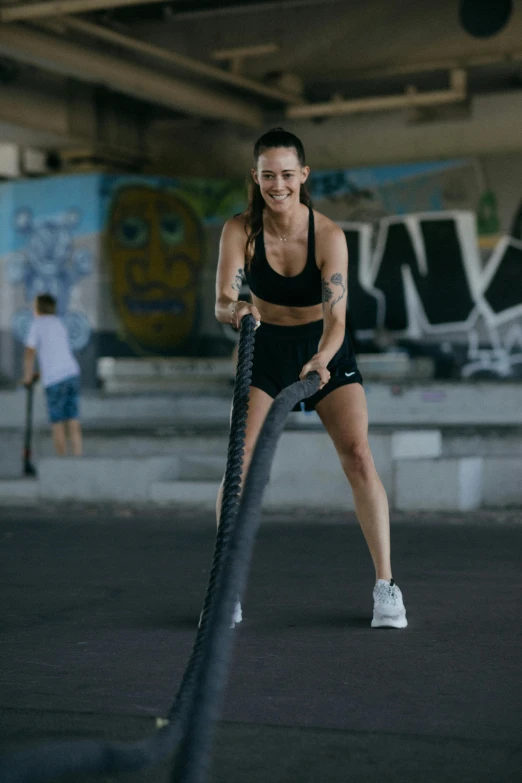 a woman holding a rope in a parking lot, working out, sanja stikovic, having a good time, asher duran