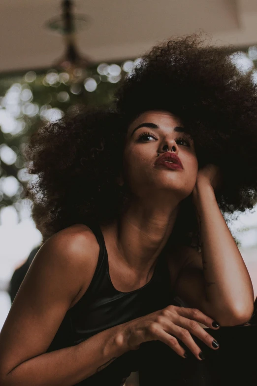 a woman with an afro sitting on a bench, trending on pexels, hair texture, focused on her neck, sassy pose, half image