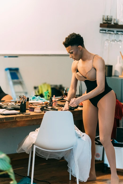 a woman that is standing in front of a table, by Emanuel Witz, featured on instagram, process art, wearing leotard, theater dressing room, in a black betch bra, sculpting