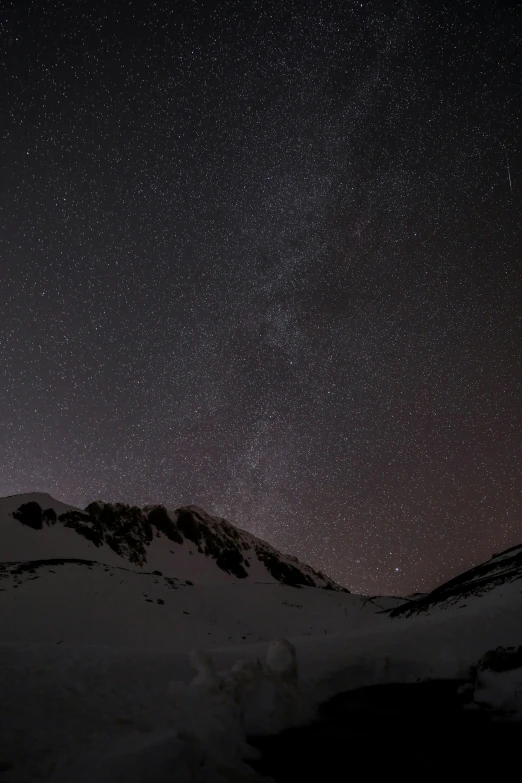 a person standing on top of a snow covered mountain under a night sky, today\'s featured photograph 4k, balaskas, grey