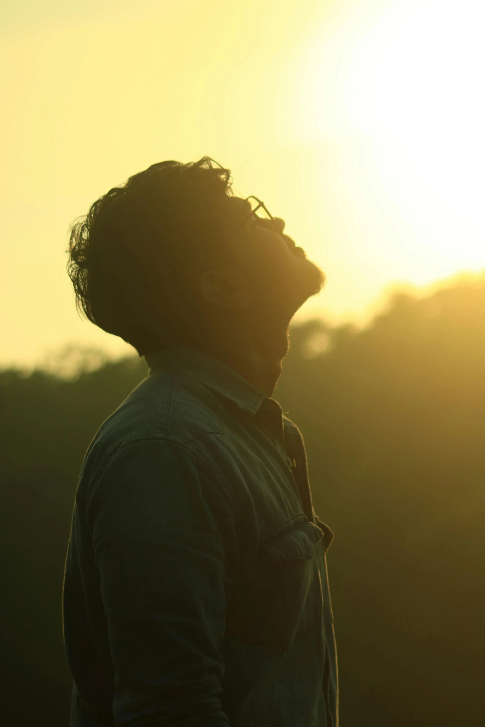 a man standing in front of a sunset, movie still of a tired, jayison devadas, backlit golden hour, head bowed slightly