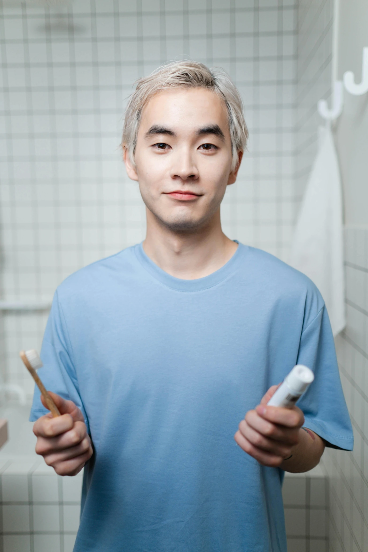 a man standing in a bathroom holding two toothbrushes, inspired by Tooth Wu, reddit, hyperrealism, white-hair pretty face, ethnicity : japanese, shaven face, professionally color graded