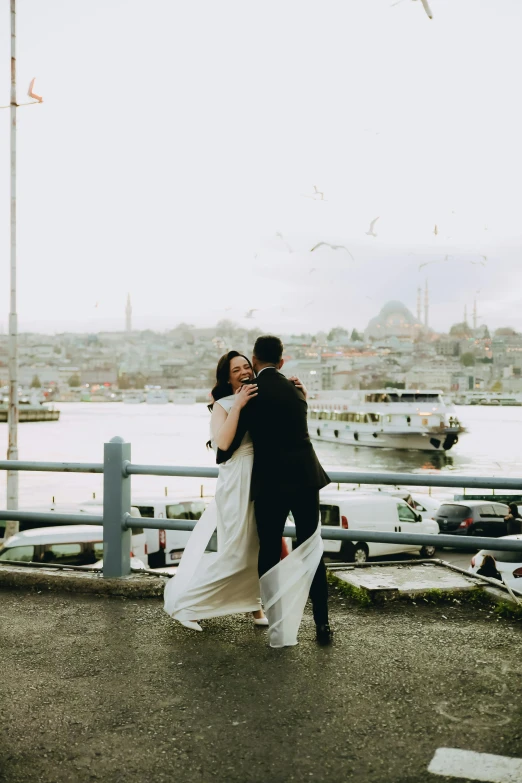 a man and a woman standing next to each other on a bridge, pexels contest winner, happening, turkish and russian, hugging, harbour in background, wedding