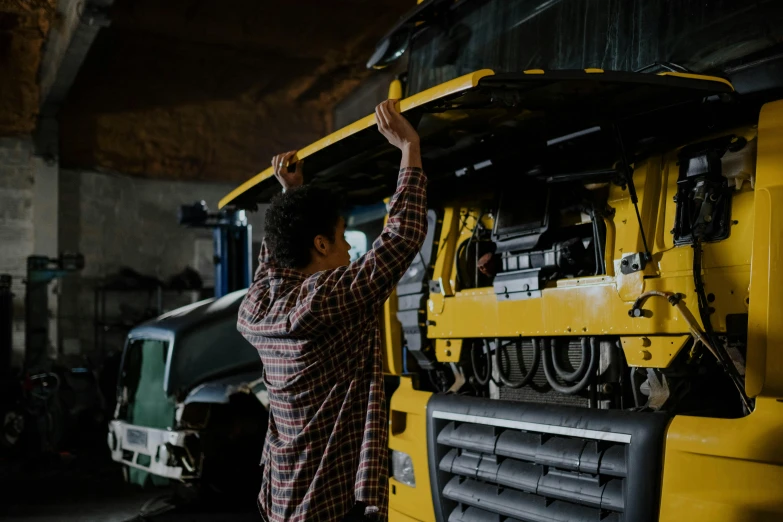 a man that is standing in front of a truck, pexels contest winner, repairing the other one, yellow and charcoal, underbody, avatar image