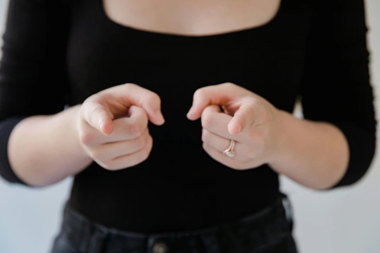 a close up of a person holding something in their hands, by Emma Andijewska, trending on pexels, wearing a black shirt, inviting posture, smallest waistline, sarcastic pose