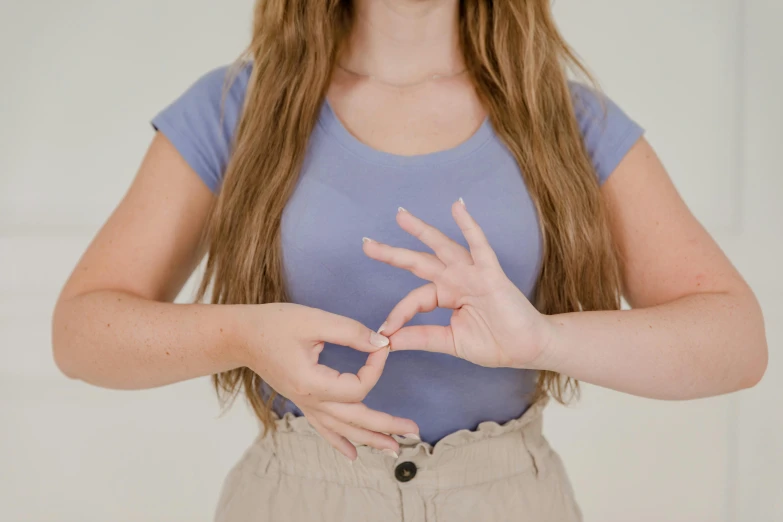 a woman making a heart sign with her hands, trending on pexels, 5 points of articulation, triangle to use spell, 18 years old, swollen muscles