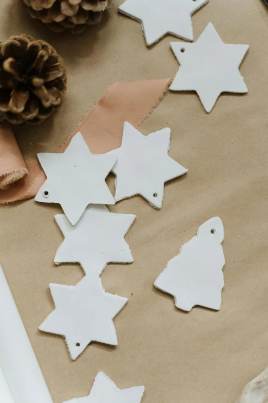 a close up of christmas decorations on a table, by Elsie Henderson, trending on pexels, process art, white clay, labels, stars, close-up product photo