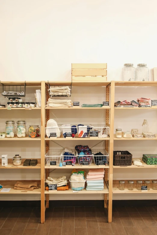 a shelf filled with lots of items on top of a wooden floor, jars, cloth, sustainable materials, the store