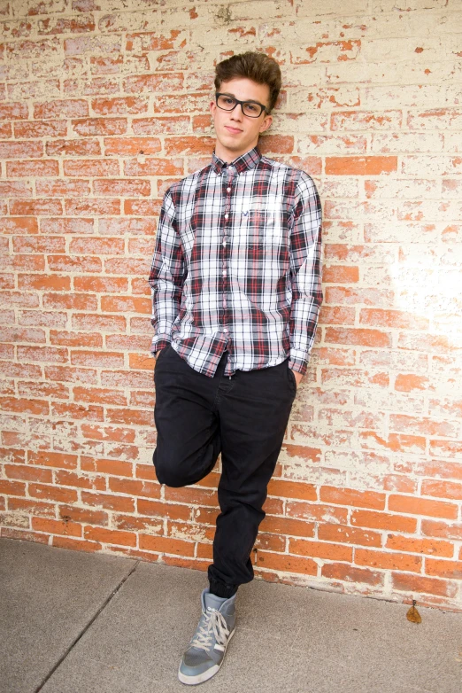 a young man standing in front of a brick wall, by Robbie Trevino, happening, plaid shirt, full lenght shot, teenager, kevin hou