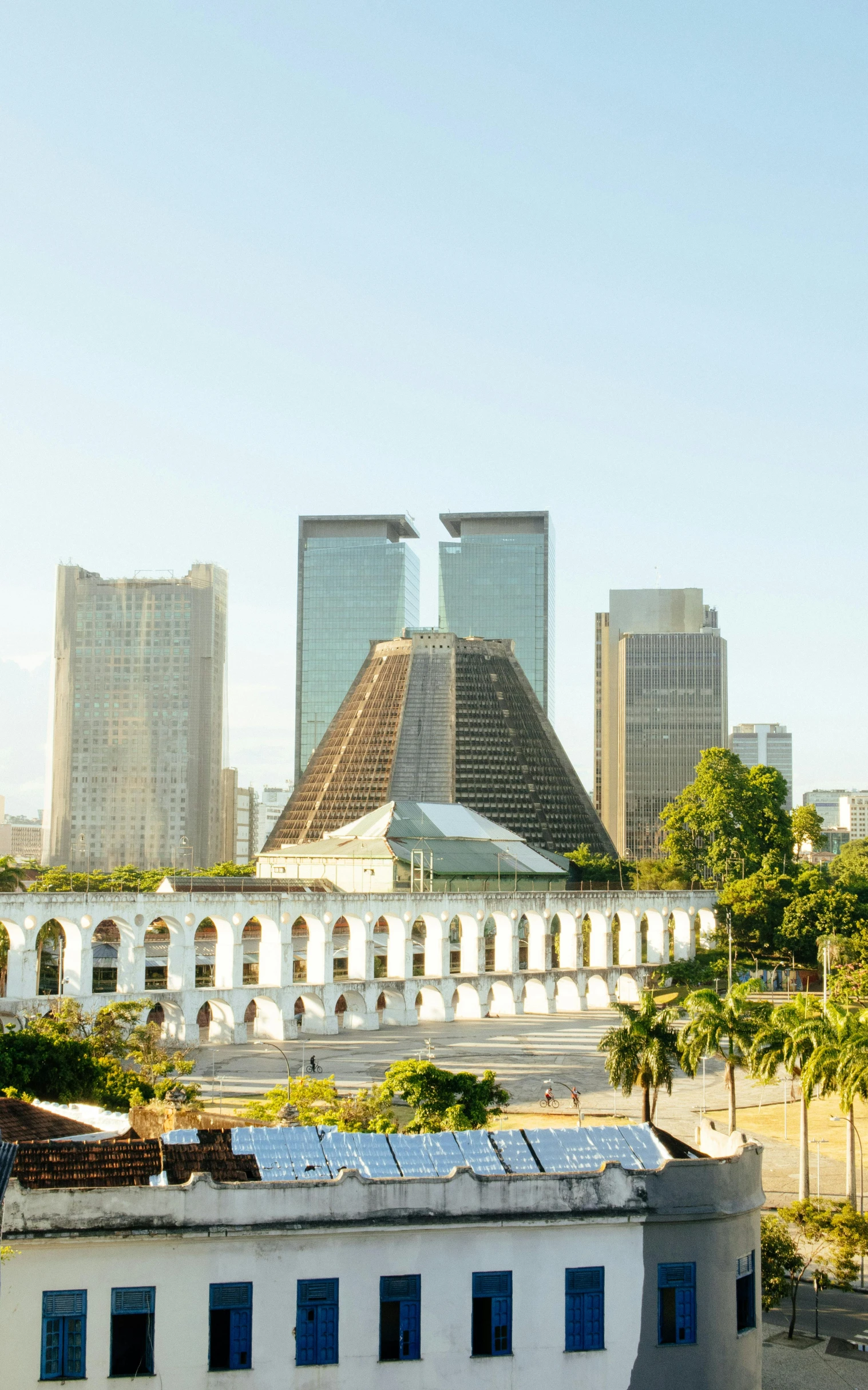 a large white building sitting in the middle of a city, by Willard Mullin, pexels contest winner, oscar niemeyer, pyramid in background, panorama, tyndall rays