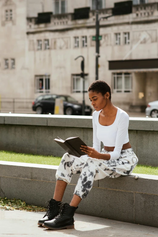 a woman sitting on a ledge reading a book, by Nina Hamnett, happening, street wear, wearing a crop top, wearing off - white style, riyahd cassiem