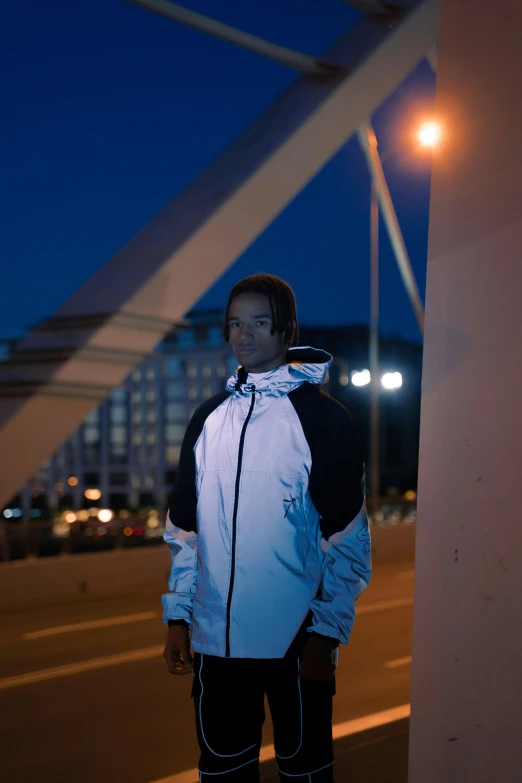 a man standing on a bridge at night, an album cover, by Barthélemy Menn, unsplash, realism, wearing a track suit, reflective puffy coat, model is wearing techtical vest, dramatic white and blue lighting