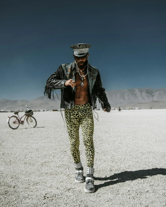 a man standing in the middle of a desert, inspired by David LaChapelle, trending on unsplash, maximalism, wearing studded leather, picture of a male biker, jeweled costume, wearing only pants