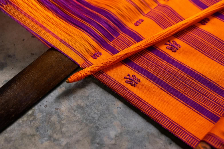 an orange and purple umbrella sitting on top of a table, by Gina Pellón, one of the weavers of destiny, high technical detail, sarong, webbing