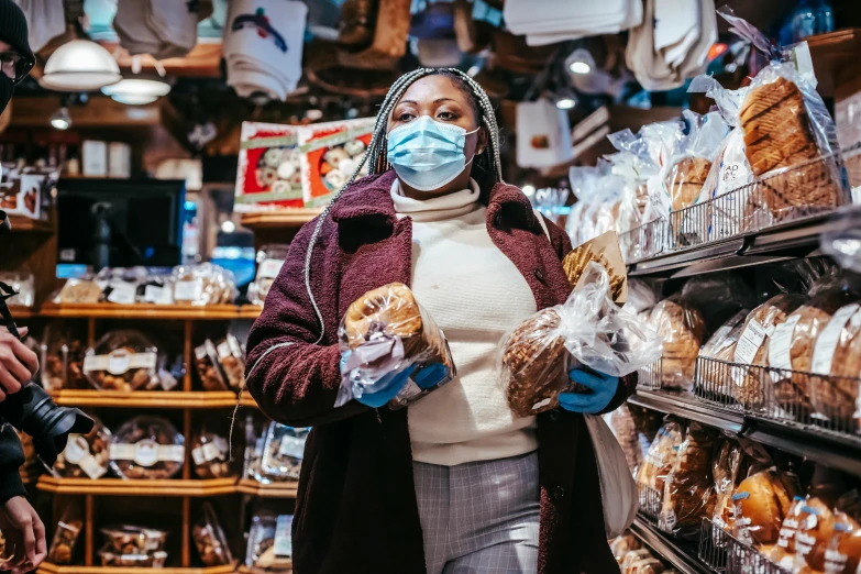 a woman wearing a face mask in a grocery store, by Julia Pishtar, pexels, holding toasted brioche bun, photo of a black woman, humans of new york, loaves