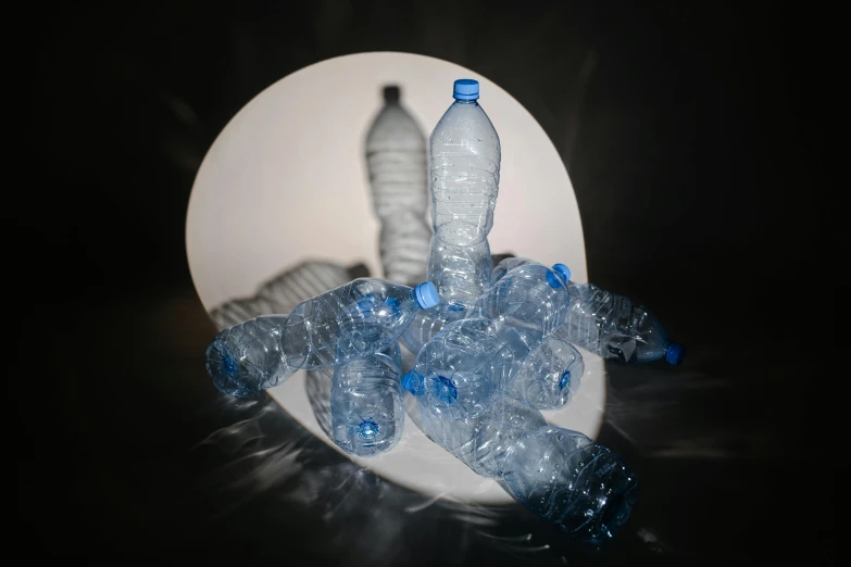 a pile of plastic bottles sitting on top of a table, an album cover, inspired by Anna Füssli, volumetric backlighting, water reflection, 2022 photograph, ((still life))