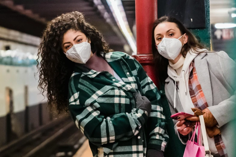 a couple of women standing next to each other on a train platform, trending on pexels, graffiti, masked doctors, polluted, people shopping, pixar coronavirus movie