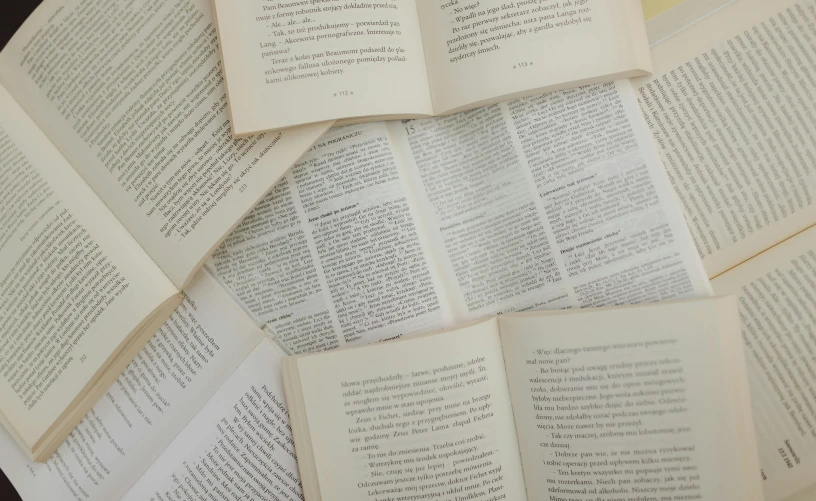 a pile of open books sitting on top of a table, by Carey Morris, unsplash, private press, text paragraphs in left, on vellum, passages, english text