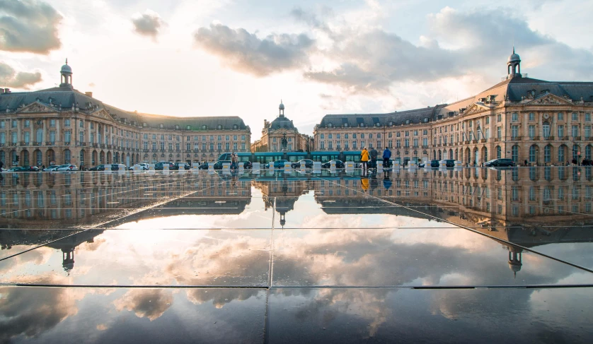 a reflection of a building in a puddle of water, by Raphaël Collin, pexels contest winner, neoclassicism, square, travel guide, unsplash 4k, rennes - le - chateau