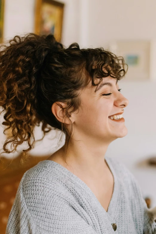 a woman is smiling while holding a cat, trending on pexels, curly bangs and ponytail, mutahar laughing, profile image, slightly pixelated