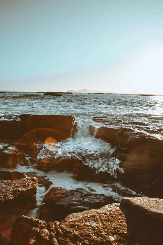 a large body of water sitting on top of a rocky beach, pexels contest winner, romanticism, ocean spray, sunlit, charybdis, low quality photo