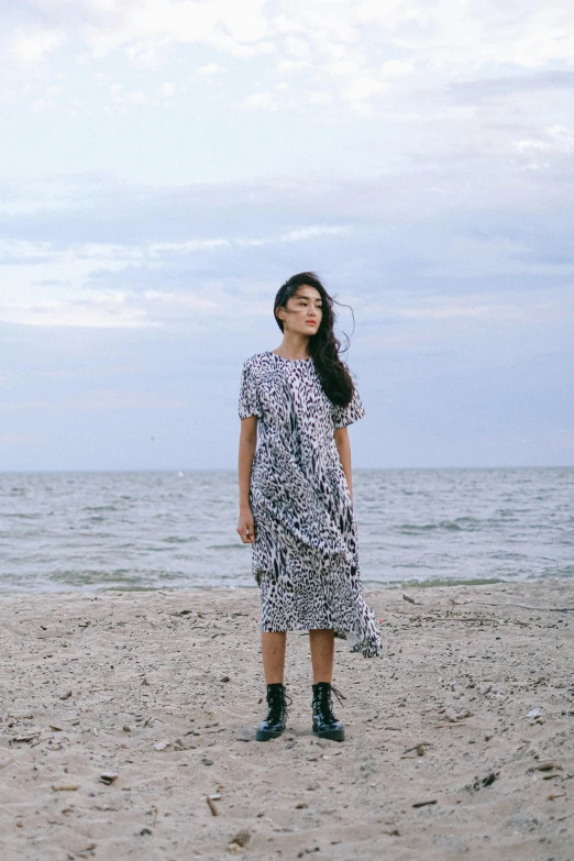 a woman standing on a beach next to the ocean, inspired by Sasha Putrya, happening, patterned clothing, grimes, official store photo, irregular