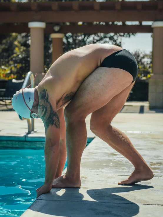 a man getting ready to dive in a swimming pool, by Jessie Alexandra Dick, unsplash, renaissance, bent over posture, 3/4 side view, taken on a 2010s camera, thicc