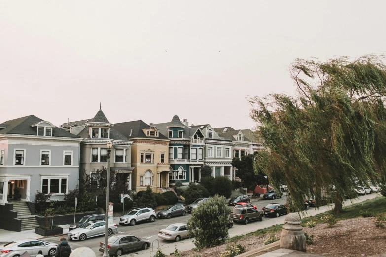 a street filled with lots of parked cars, a photo, by Carey Morris, unsplash, victorian architecture, bushes in the background, bay area, background image