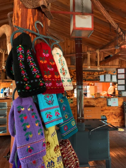 a bunch of sweaters hanging on a pole in a room, a photo, by Terese Nielsen, folk art, pilgrim village setting, 🦩🪐🐞👩🏻🦳, bright vivid colors, longhouse