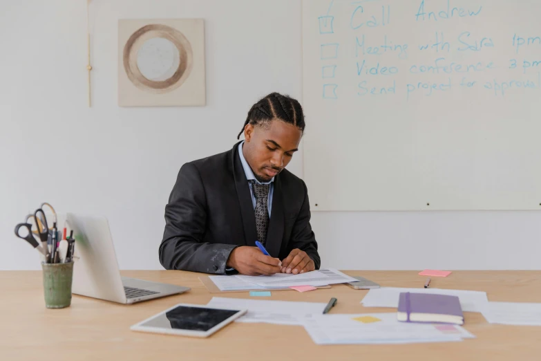 a man sitting at a table writing on a piece of paper, pexels contest winner, afro tech, whiteboards, lawyer, lachlan bailey