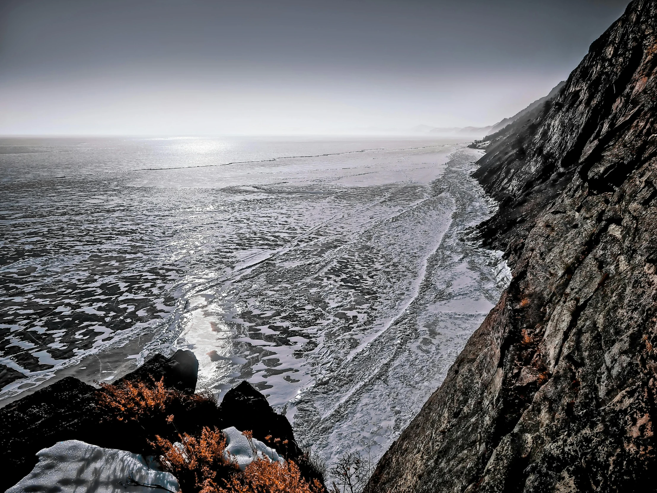 a man standing on top of a cliff next to the ocean, by Jeffrey Smith, unsplash contest winner, romanticism, scary sharp icy, a photo of the ocean, high textured, deep colours. ”