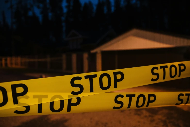 a close up of a yellow tape with a house in the background, a picture, shutterstock, homicide, night photo, f/stop, ap news photograph