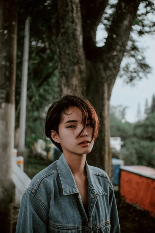 a young man standing in front of a tree, inspired by Elsa Bleda, pexels contest winner, realism, young asian woman, short hair on sides of head, attractive girl tomboy, beautiful grumpy girl