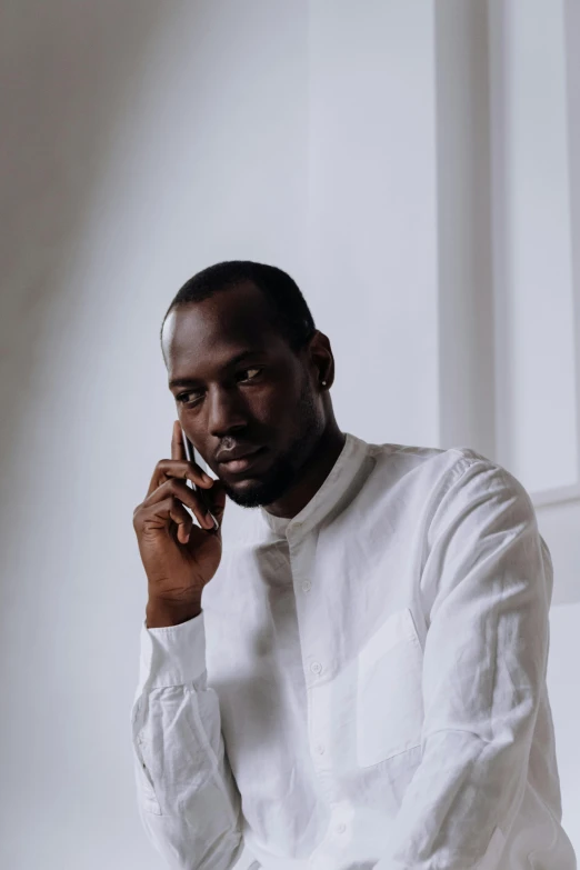 a man in a white shirt talking on a cell phone, inspired by Theo Constanté, pexels contest winner, adut akech, herzog de meuron, ( ( dark skin ) ), grey