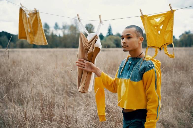 a man standing in a field holding a bunch of clothes, pexels contest winner, renaissance, yellow overall, laundry hanging, wearing a track suit, avatar image