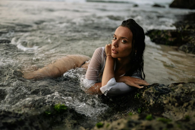 a woman laying on a rock in the water, profile pic, modelling, wet boody, drenched clothing