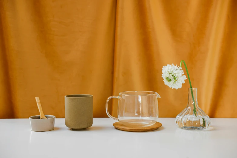 a white table topped with a vase filled with flowers, inspired by Constantin Hansen, featured on pinterest, minimalism, moroccan tea set, liquid translucent amber, from left, wearing wheat yellow gauze